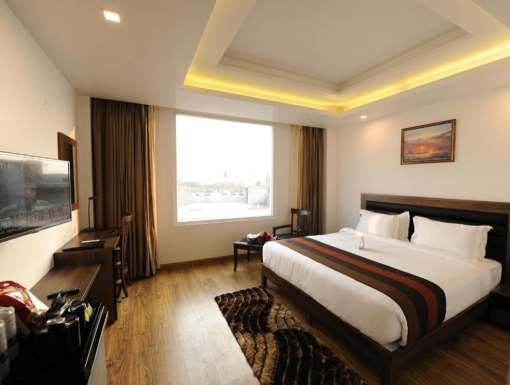 a hotel room with a bed and a large window at Hotel Abode in Amritsar