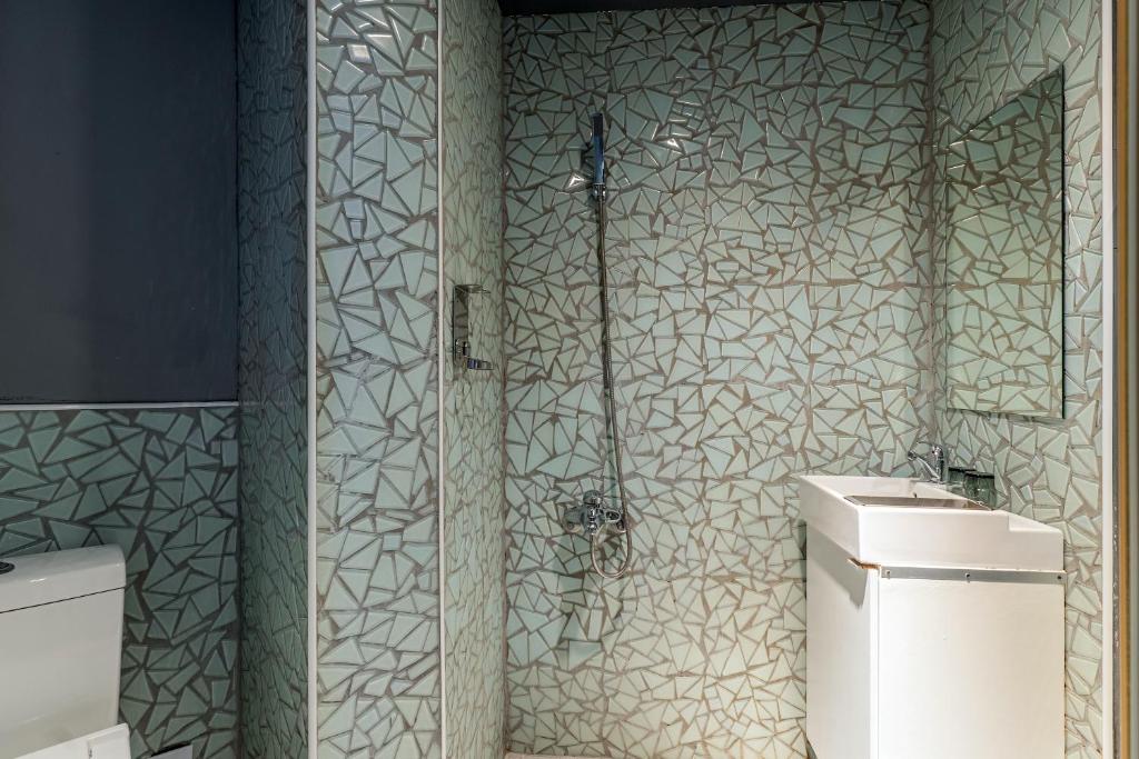 a shower in a bathroom with green and white tiles at CHECK inn Taichung Liming in Taichung