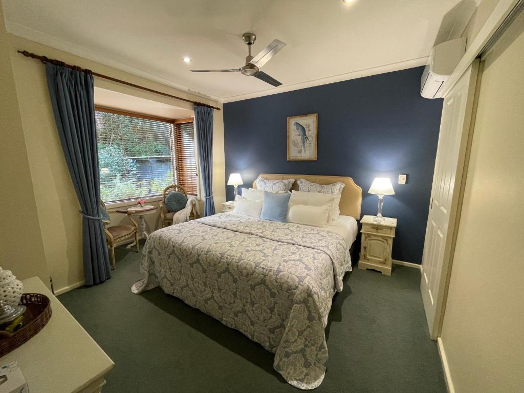 a bedroom with a bed with blue walls and a window at Rosewood Guesthouse in Margaret River Town