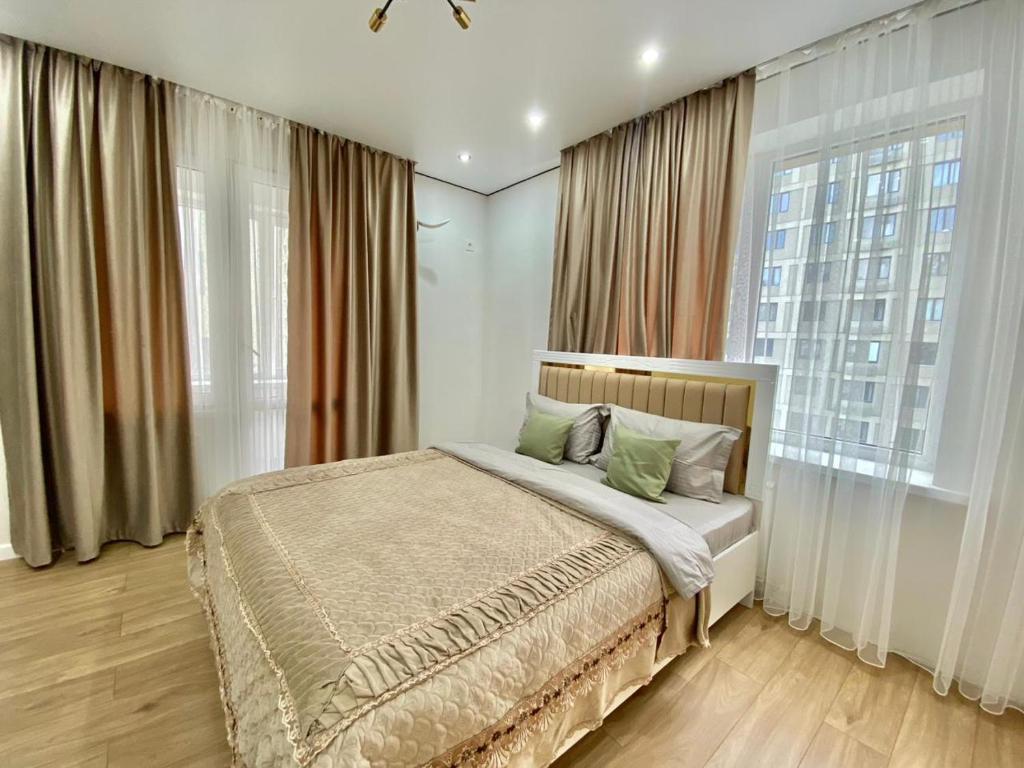 um quarto com uma cama e uma grande janela em Однокомнатные апартаменты ЖК Auezov city 37 em Almaty
