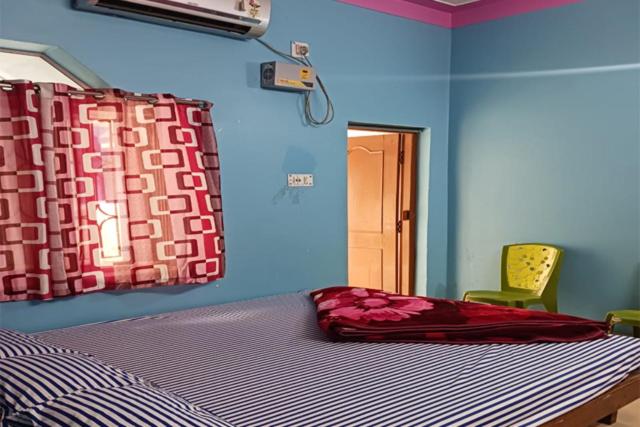 a bedroom with a bed and a window and a chair at HOTEL NAKSHATRA in Digha