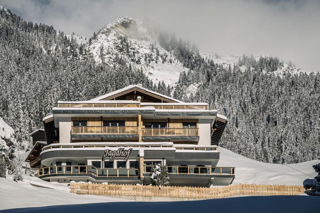 ein Gebäude im Schnee vor einem Berg in der Unterkunft Jagdhof PURE Mountain Appartements in Tux