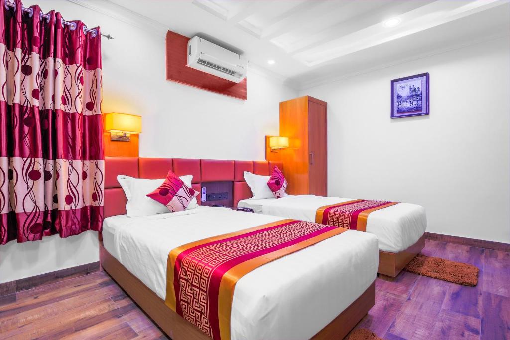 two beds in a room with red and white at Hotel Intourist Palace in Itahari