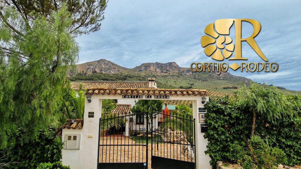 a gate in front of a building with a sign at Cortijo Rodeo. Alojamiento Rural in Carcabuey