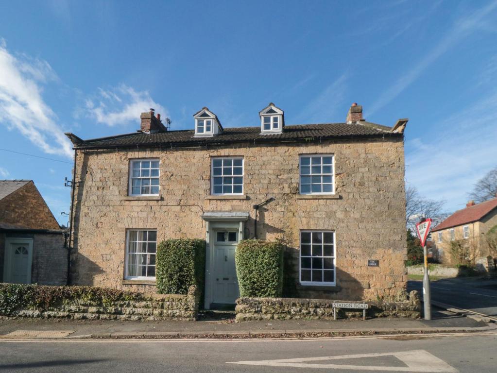 uma casa de tijolos com uma porta azul numa rua em The Lodge em Snainton