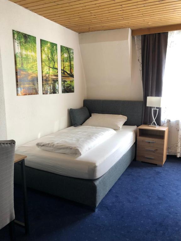 ein Bett in einem Schlafzimmer mit zwei Bildern an der Wand in der Unterkunft Hotel Weismann in Sankt Georgen im Attergau