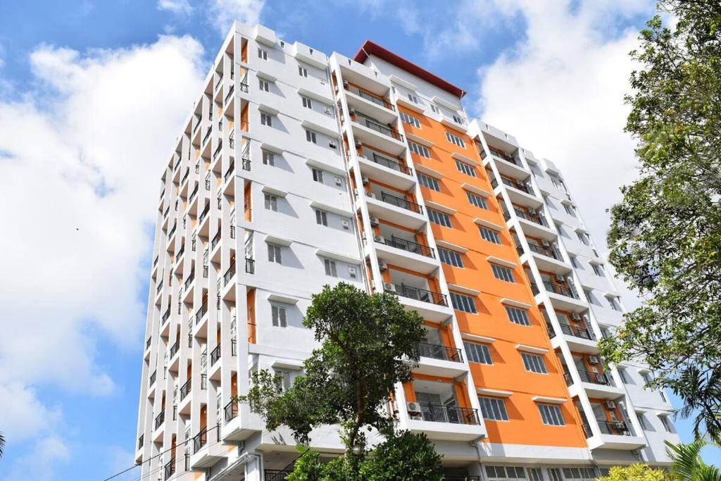 an orange and white building with trees in the foreground at Rush Reliance Mt. Lavinia in Attidiya