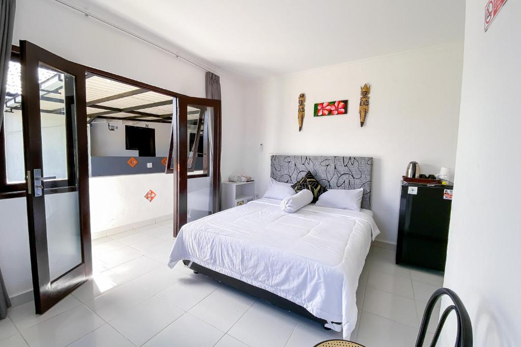 a bedroom with a white bed and a sliding glass door at Kana Guest House Mitra RedDoorz in Uluwatu