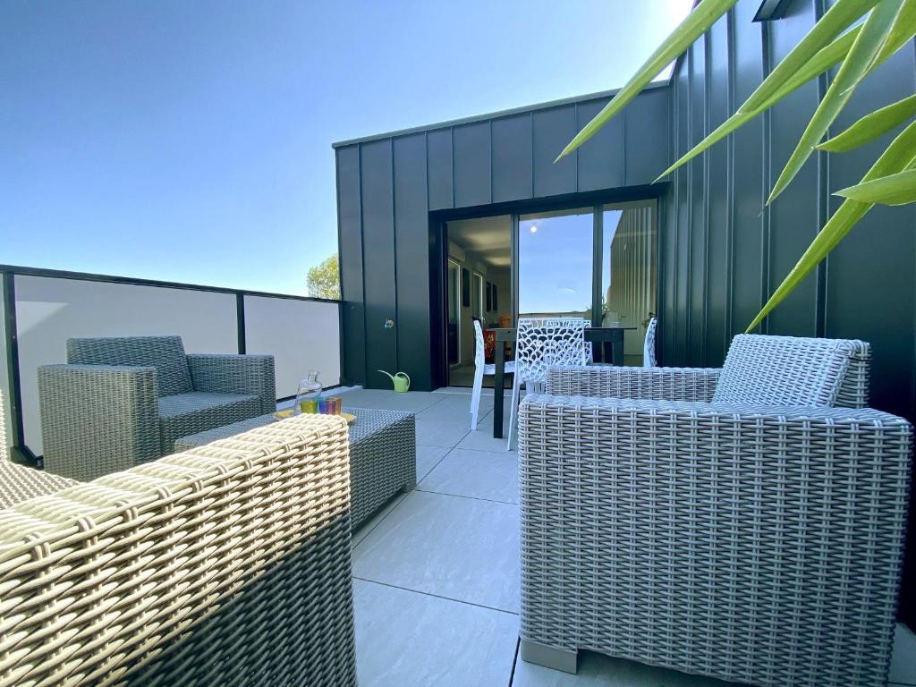 un patio avec des chaises et des tables en osier dans un bâtiment dans l'établissement Appartement 3 pièces avec terrasse, proche plage, parking, ascenseur – Pornichet - FR-1-306-1226, à Pornichet