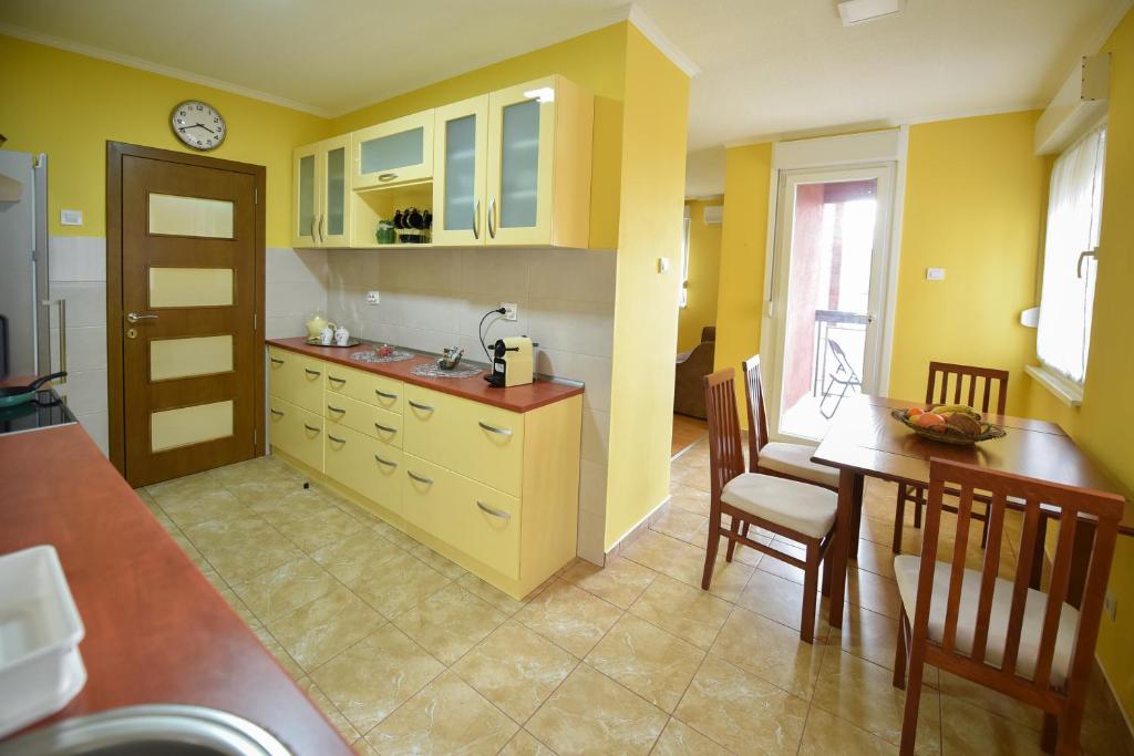 a kitchen with yellow walls and a table and chairs at Apartman Odzaci in Odžaci