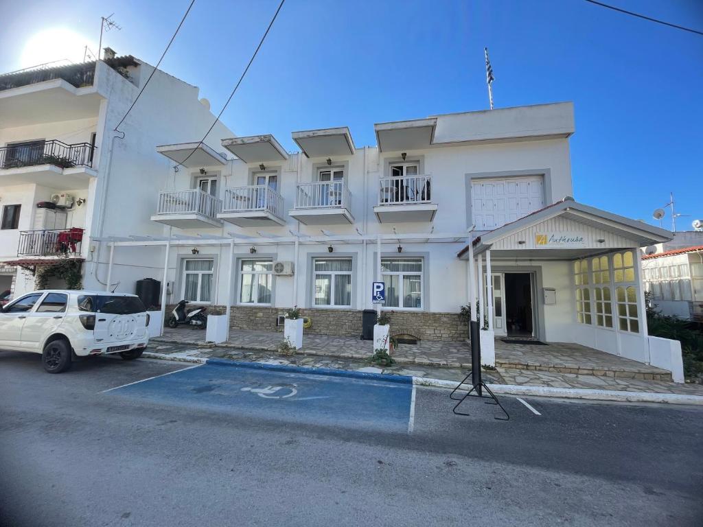 a white building with a truck parked in front of it at Hotel Anthousa in Samos