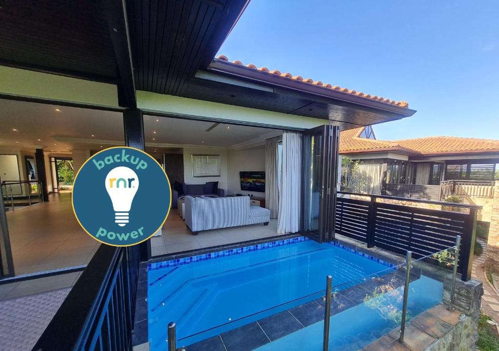 a swimming pool in front of a house with a sign at Zimbali - Luxury 4 Bedroom KRH1 in Ballito