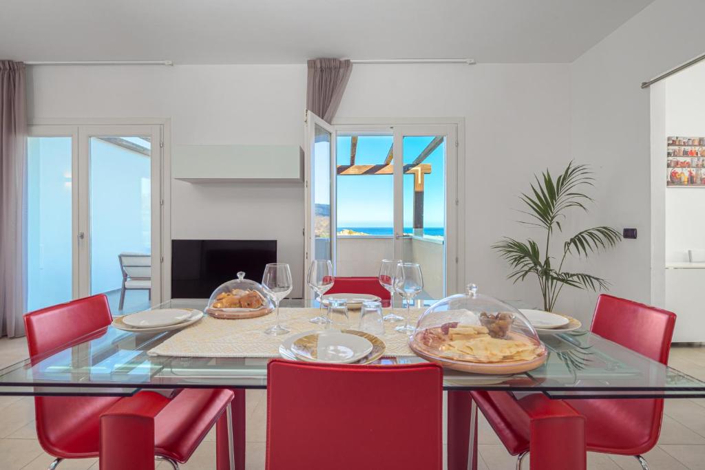 a dining room with a glass table with red chairs at Villa Marconi Apartment 7 in Golfo Aranci