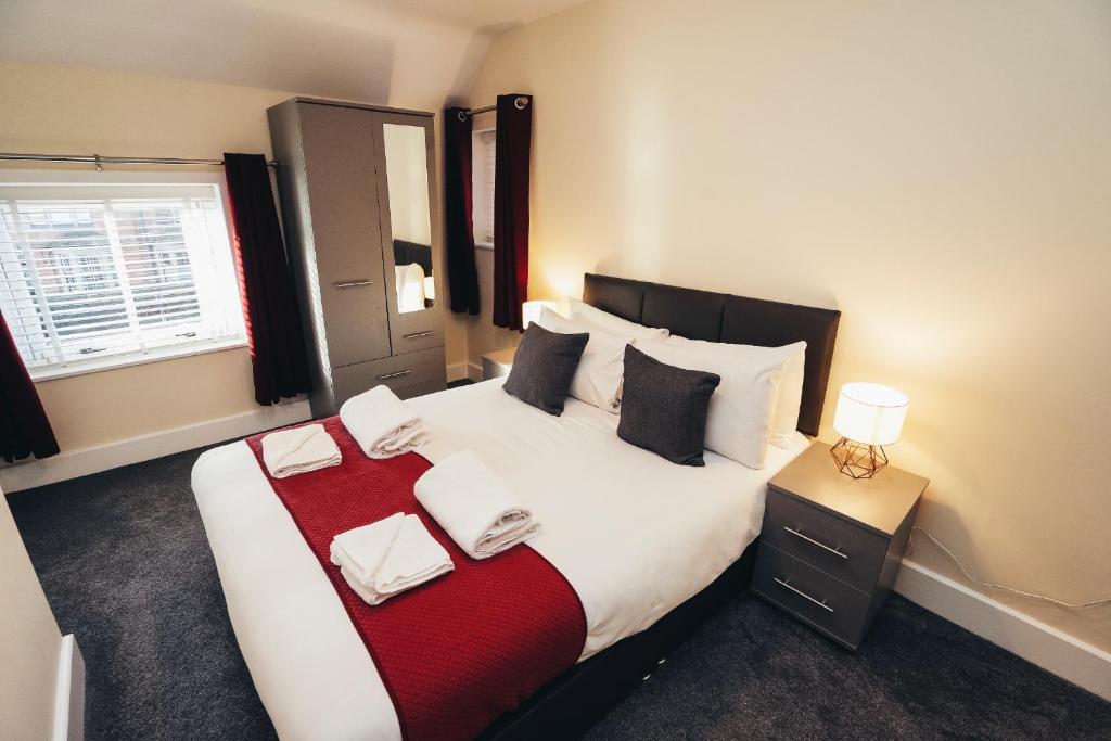 a bedroom with a large bed with a red blanket at The Stay Company, Friar Gate Bridge. in Derby