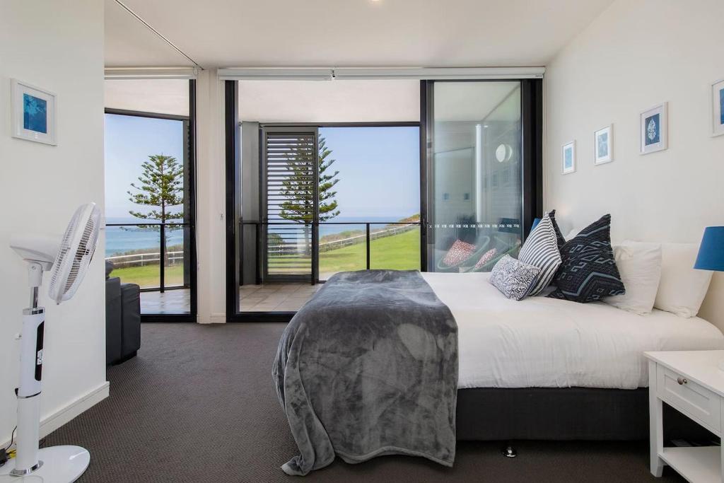 a bedroom with a bed with a view of the ocean at The Sandpiper - A Newy Beachfront Beauty in Newcastle