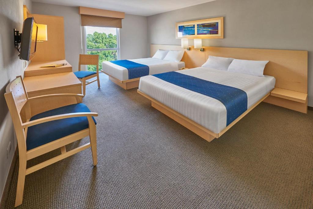 una habitación de hotel con dos camas y una silla en City Express by Marriott Puebla FINSA, en Puebla