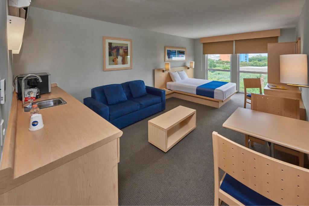 Una sala de estar con un sofá azul y una cama. en City Express by Marriott Puebla FINSA, en Puebla
