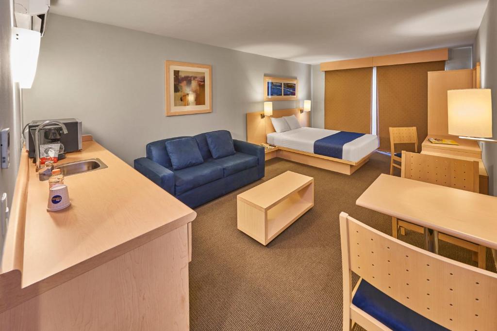 Una sala de estar con un sofá azul y una cama. en City Express by Marriott Puebla FINSA, en Puebla