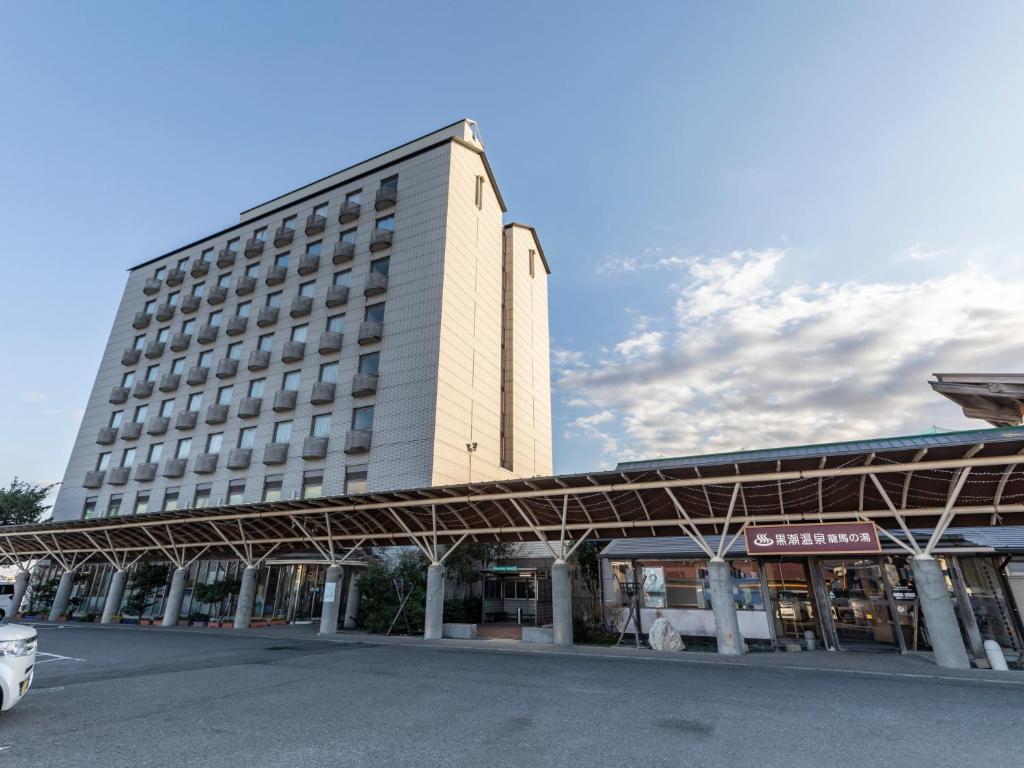 a large white building with a parking lot in front of it at Kochi Kuroshio Hotel in Konan