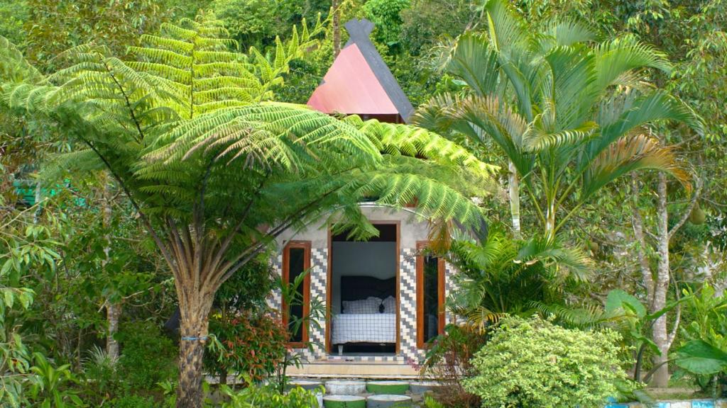 a small house in a forest with a palm tree at Goa Walet Cottage in Praya