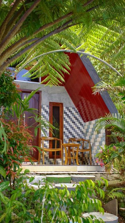 a house with two chairs and a table in front of it at Goa Walet Cottage in Praya