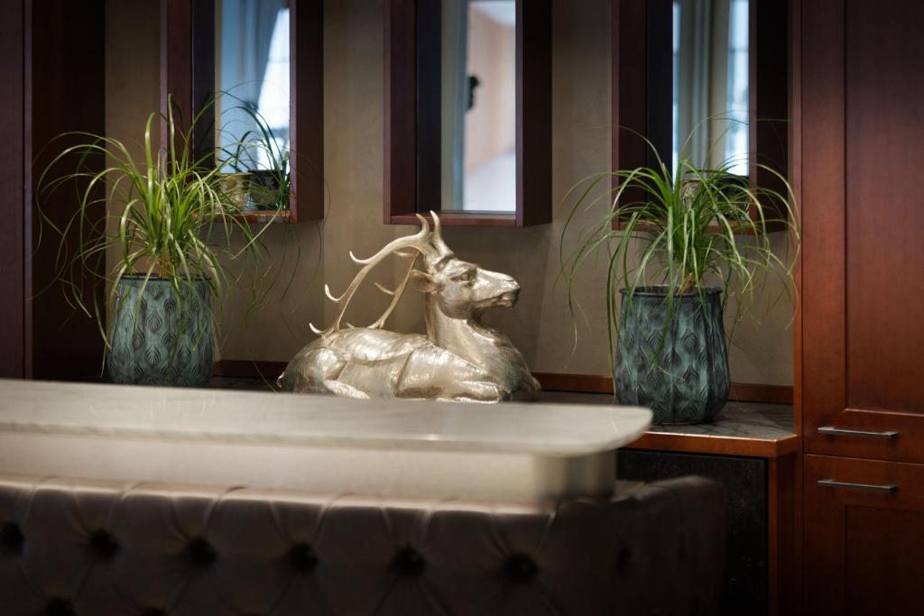 a statue of a deer in a sink with two potted plants at Arabella Jagdhof Resort am Fuschlsee, a Tribute Portfolio Hotel in Hof bei Salzburg
