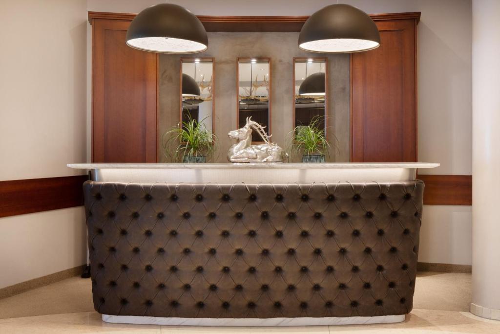 a lobby with a counter with two pendant lights at Arabella Jagdhof Resort am Fuschlsee, a Tribute Portfolio Hotel in Hof bei Salzburg