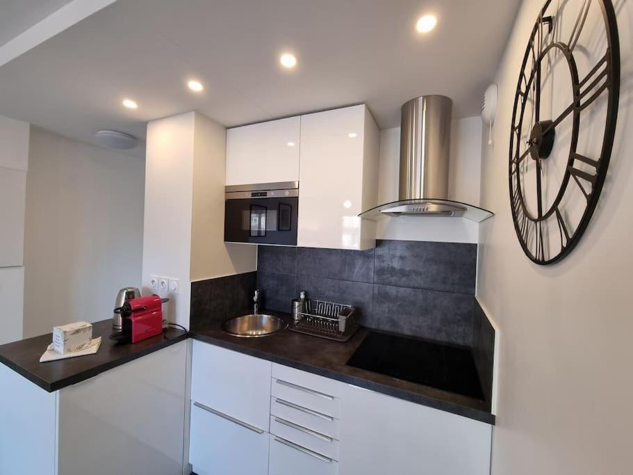 a kitchen with a large clock on the wall at Cosy Plage-Accès privé à la Mer in Cabourg