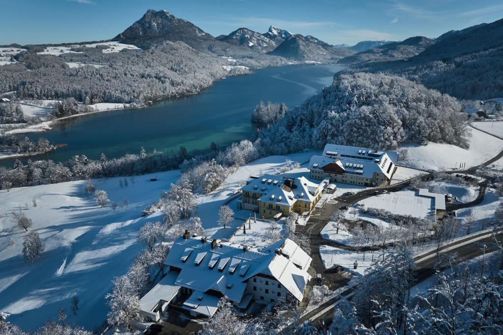 an aerial view of a house in the snow next to a lake at Arabella Jagdhof Resort am Fuschlsee, a Tribute Portfolio Hotel in Hof bei Salzburg
