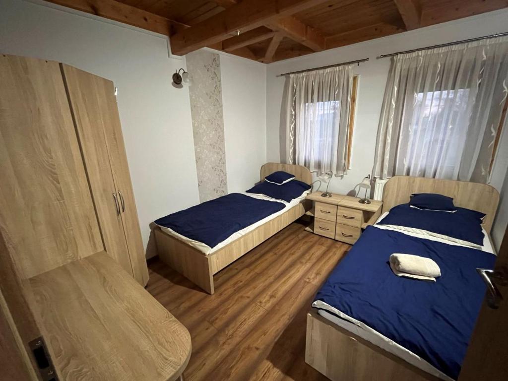 a bedroom with two beds and a wooden floor at Tisza Panzió és Apartman in Tiszaújváros