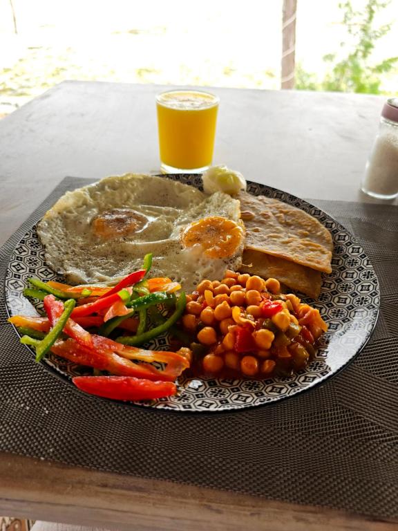 a plate of food with vegetables and a glass of orange juice at White Star Ocean View Hotel in Paje