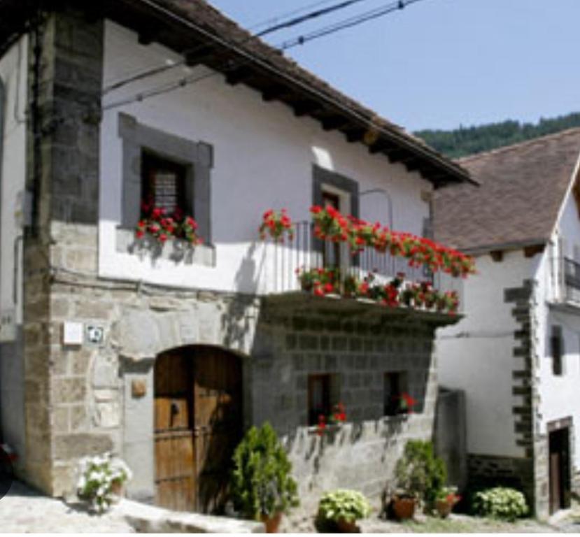 Casa blanca con flores rojas en el balcón en Casa Idiart, en Ochagavía