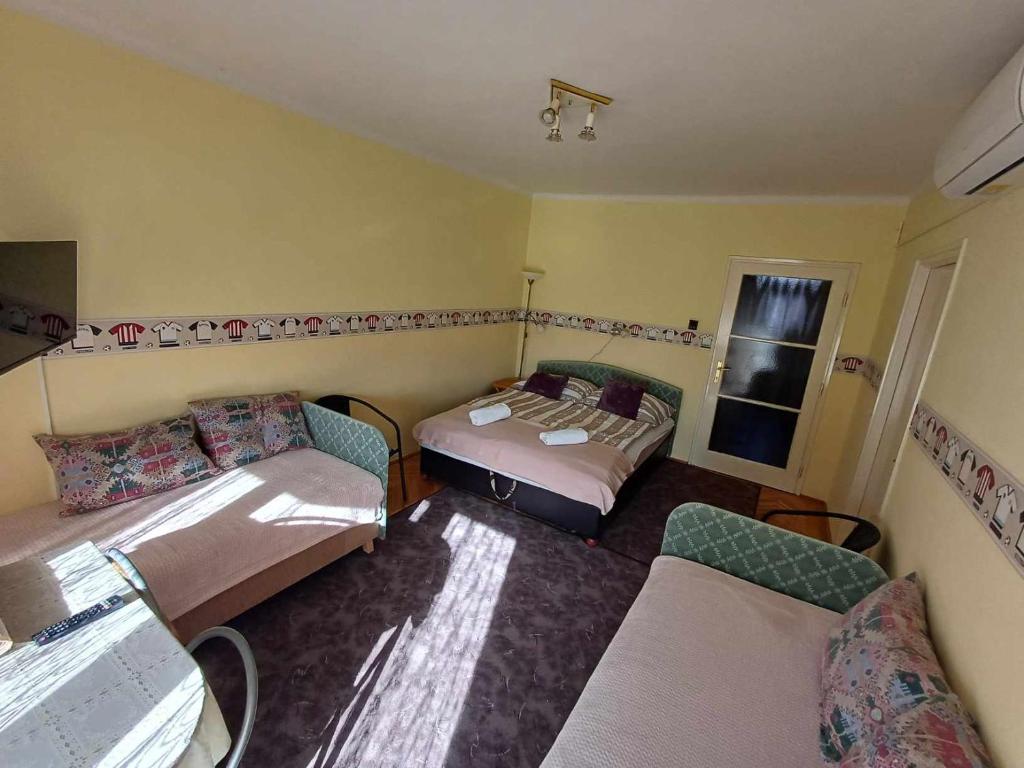 タポルツァにあるTavas Barlang Apartman Tapolcaのベッド2台とソファが備わる小さな客室です。