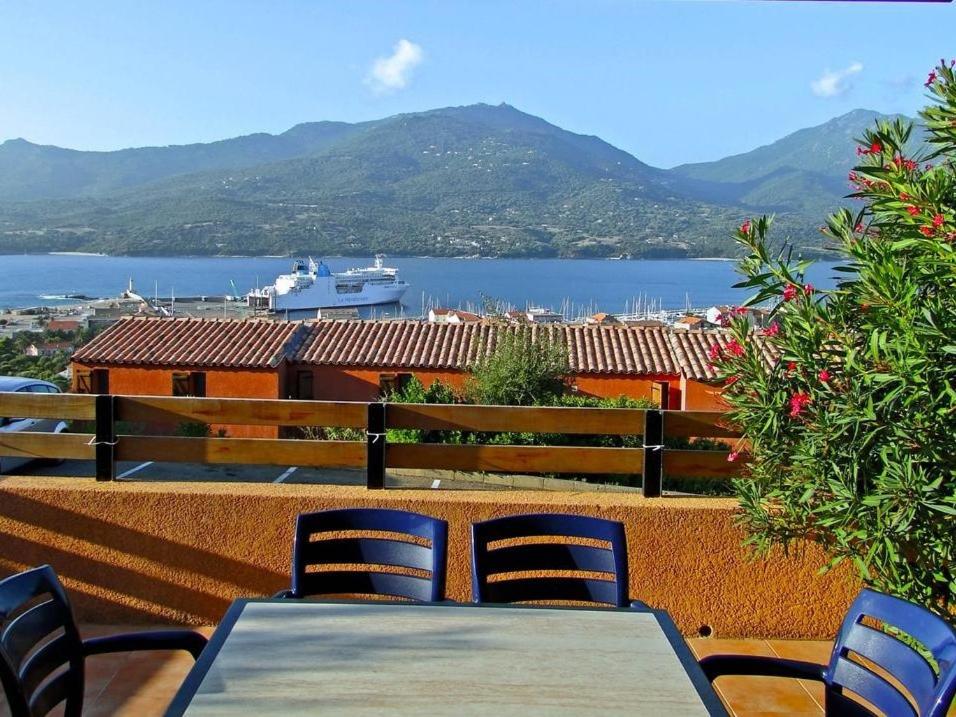 una mesa y sillas en un balcón con vistas al agua en Résidence Maquis Bella Vista, en Propriano