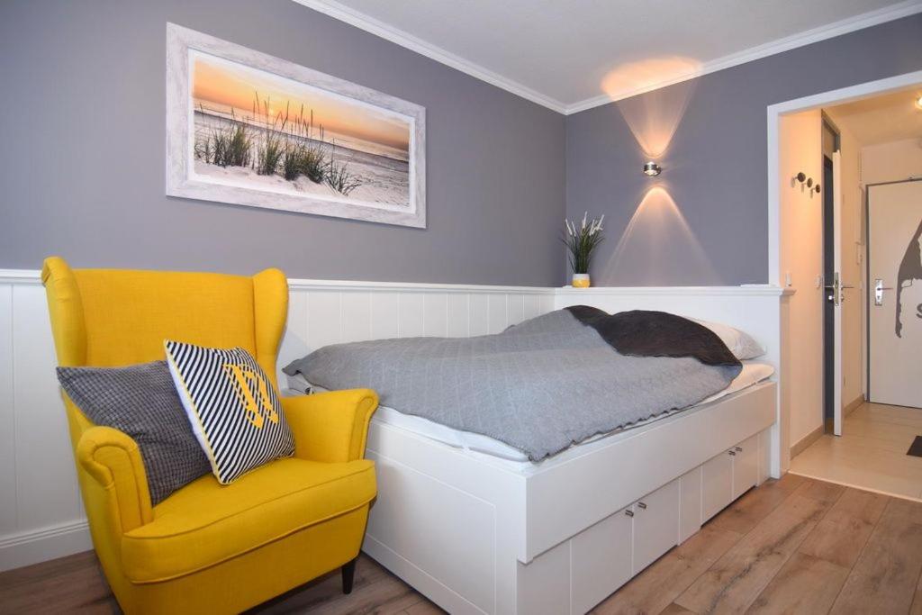 um quarto com uma cama e uma cadeira amarela em Haus am Meer, Whg 154, Landseite em Westerland