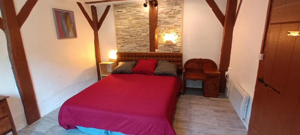 a small room with a bed with a red blanket at La suite du Bûcheron in Laharie