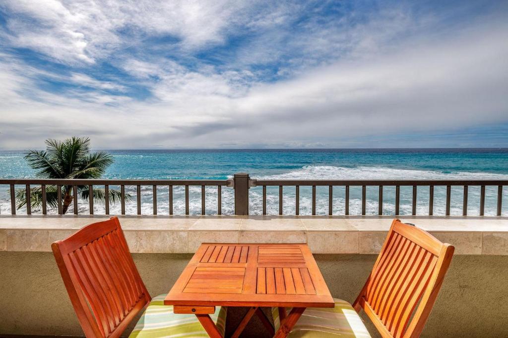 a table and two chairs on a balcony with the ocean at Banyan Tree 404D in Kailua-Kona