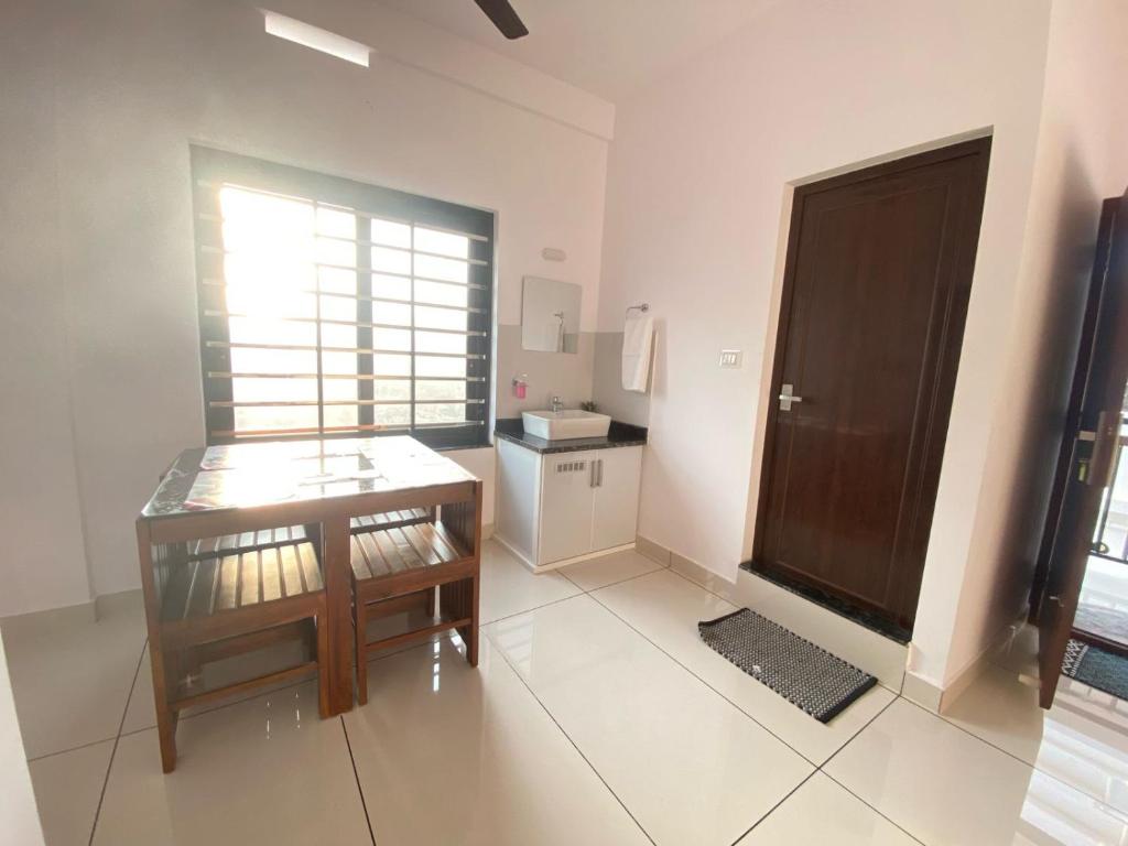 a room with a table and a small kitchen at Kandamangalath Affinity in Ernakulam