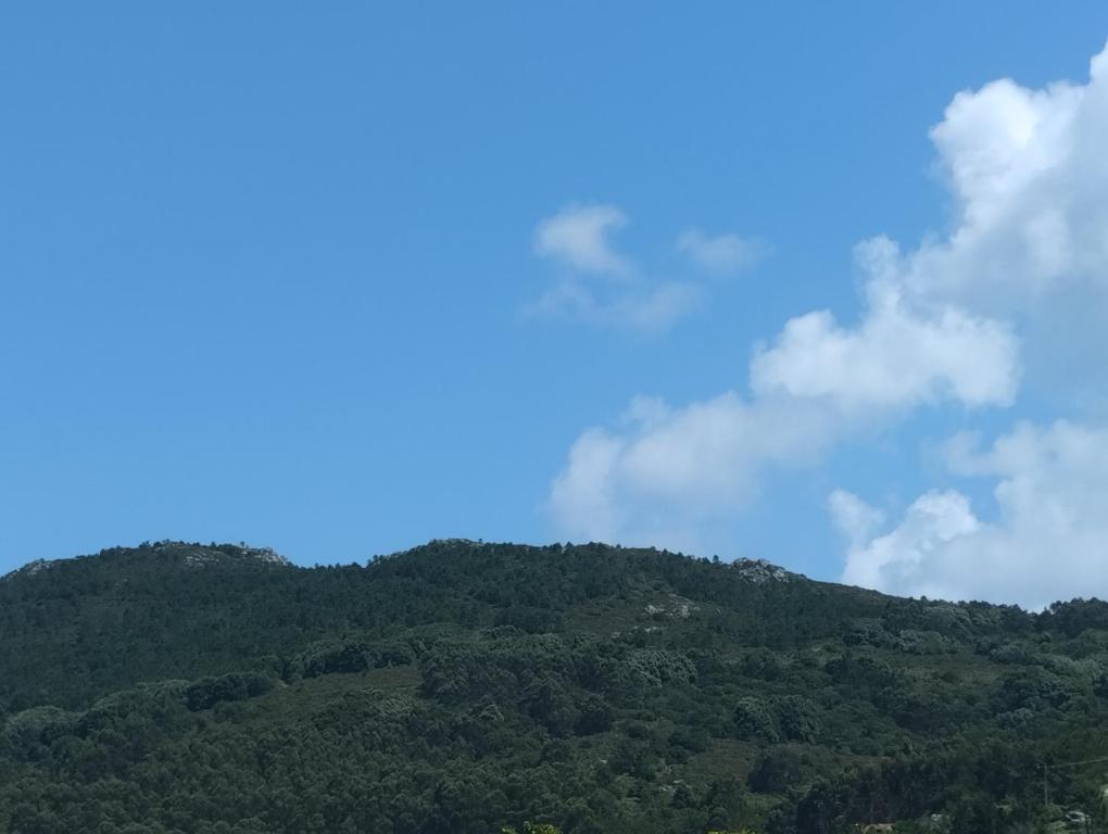 ein grüner Berg mit blauem Himmel und Wolken in der Unterkunft CASA Beirada Monte y Playa in Carnota