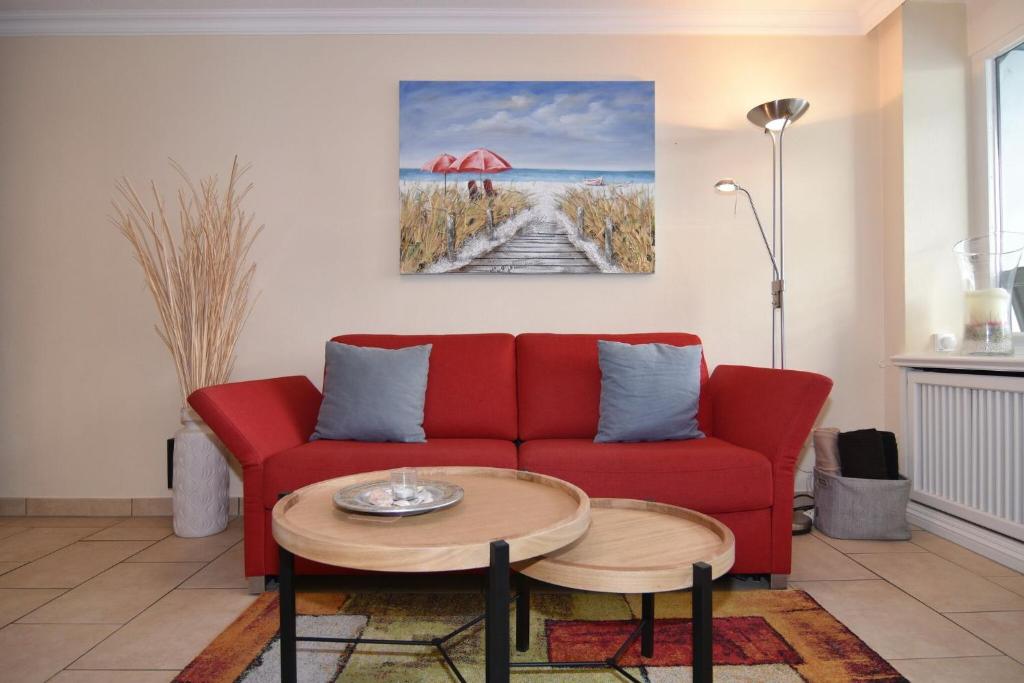 uma sala de estar com um sofá vermelho e uma mesa em Haus am Meer, Whg 92, Seeseite em Westerland