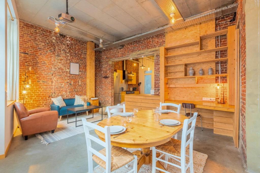 une salle à manger avec une table et un mur en briques dans l'établissement 2 bedroom souplex apartment with terrace, à Lille