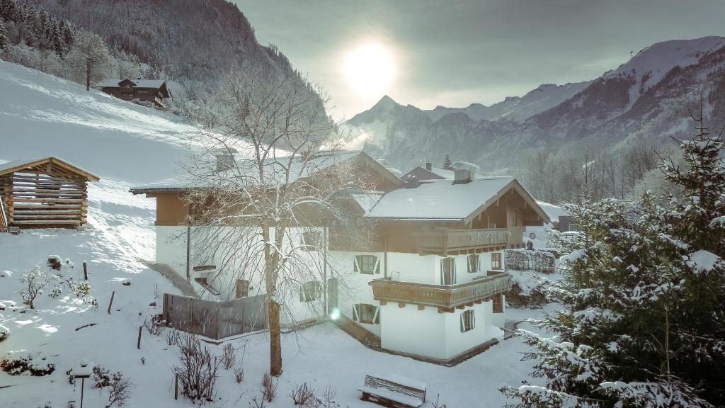a house in the snow with the sun behind it at Villa Agricola in Kaprun