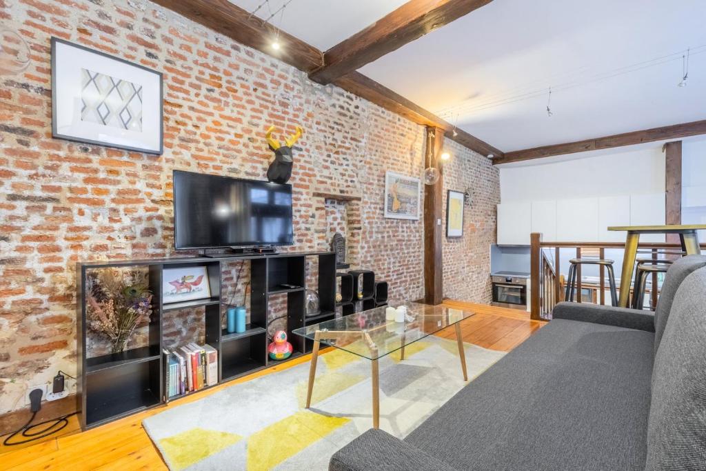 a living room with a brick wall at Atypical apartment in the heart of Old Lille! in Lille