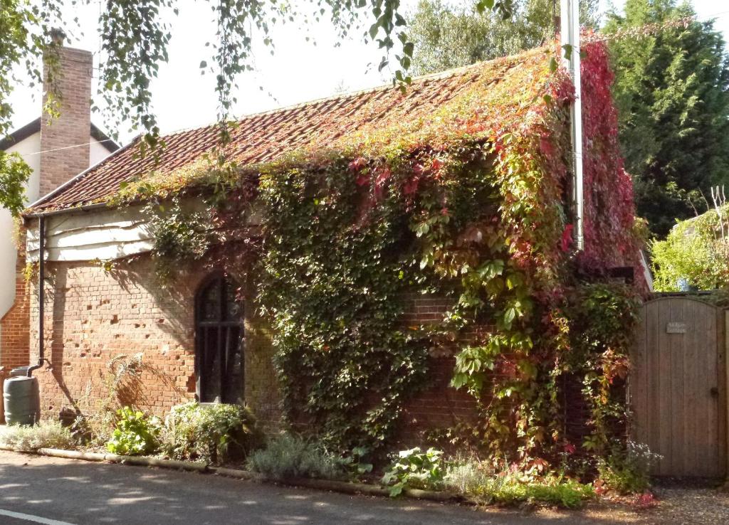 una casa di mattoni ricoperta di edera su una strada di Badger Cottage at Alde Garden a Saxmundham