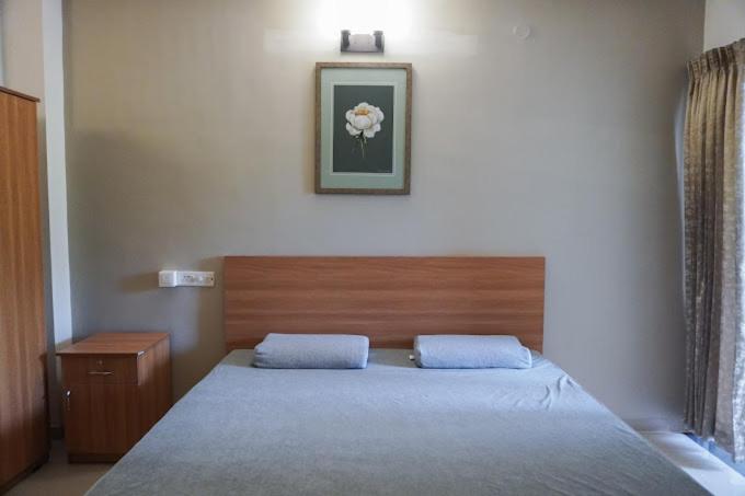 1 dormitorio con 1 cama y una foto en la pared en The Healing Hills Naturopathy and Wellness Center, en Coimbatore