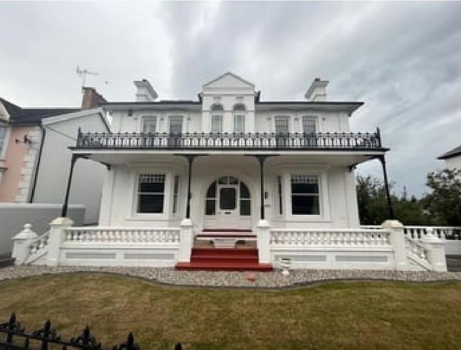 duży biały dom z werandą i czerwonymi schodami w obiekcie Hazeldene w mieście Aberaeron