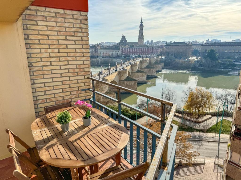 a balcony with a table and chairs and a view of the river at El Puente del Pilar ComoTuCasa in Zaragoza