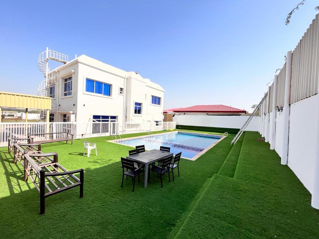 a backyard with a table and chairs and a pool at 4 Bedrooms villa for rent in Al Ḩamīdīyah