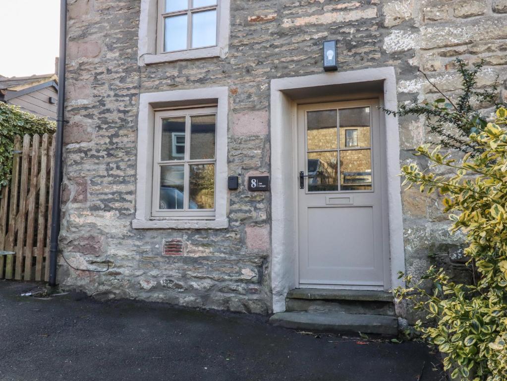 a stone house with a white door and windows at 8 Oak Cottages in Lancaster