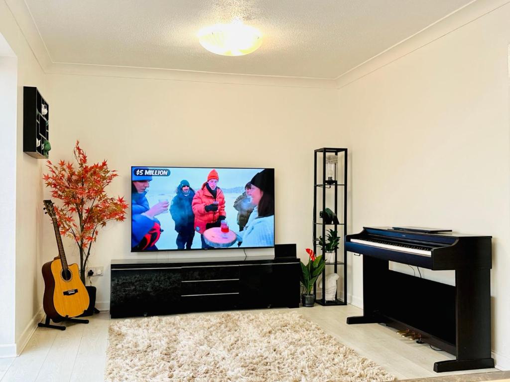 uma sala de estar com uma televisão de ecrã plano e um piano em Entire 5 bedroom detached house free Parking 5 mins driving to Bicester Village em Bicester